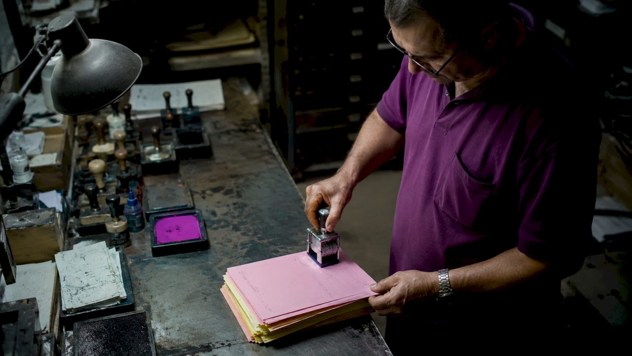Man stamping invoices with numbering stamp