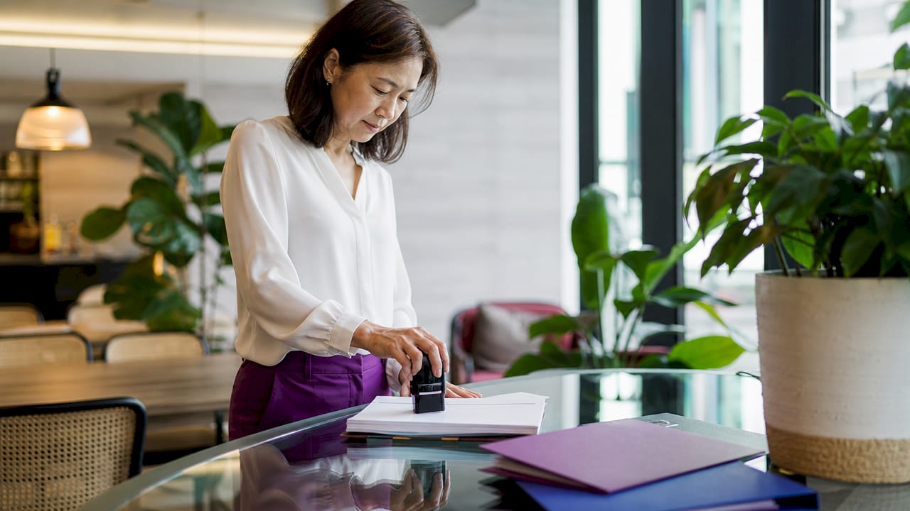 Businesswoman stamping documents at desk