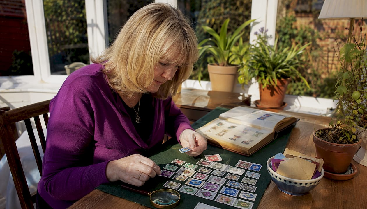 Woman examining UK commemorative stamps at home