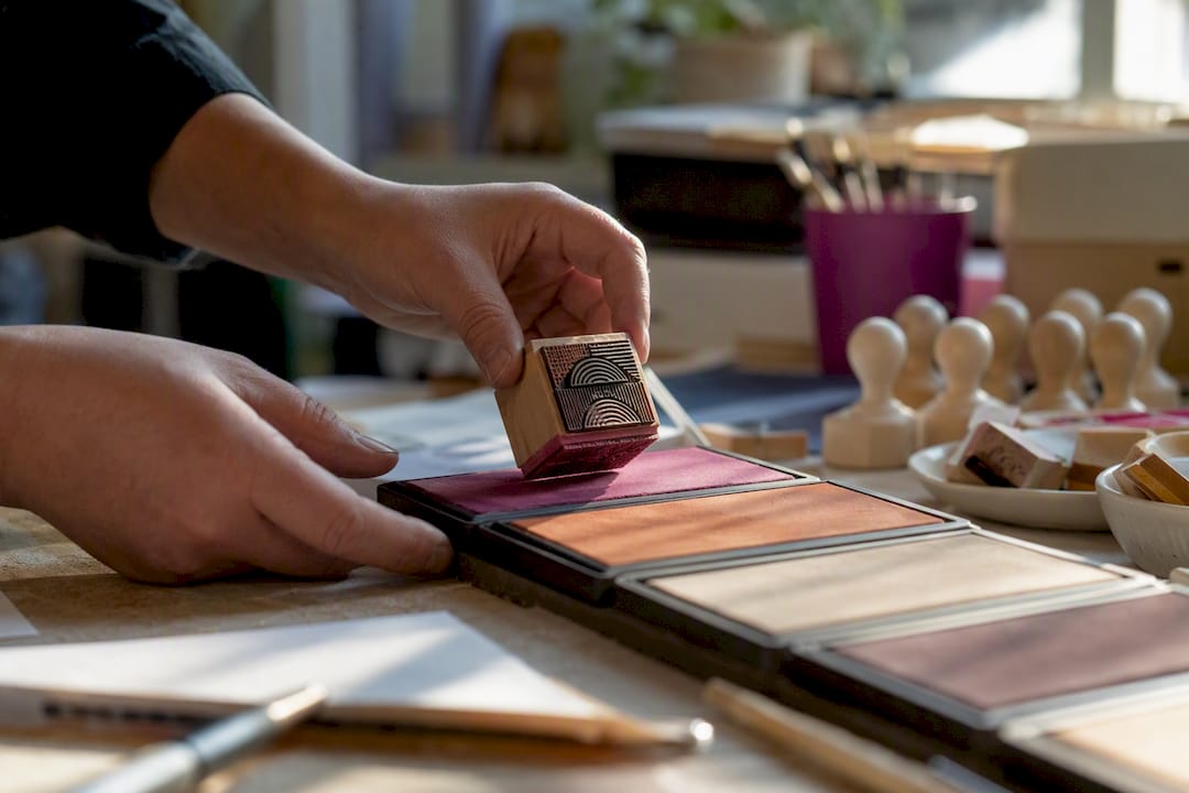 Hands pressing rubber stamp on ink pad close-up