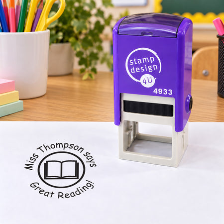 Purple SD4U 4933 Book teacher stamp on a classroom desk with a black personalised sample impression and open book design