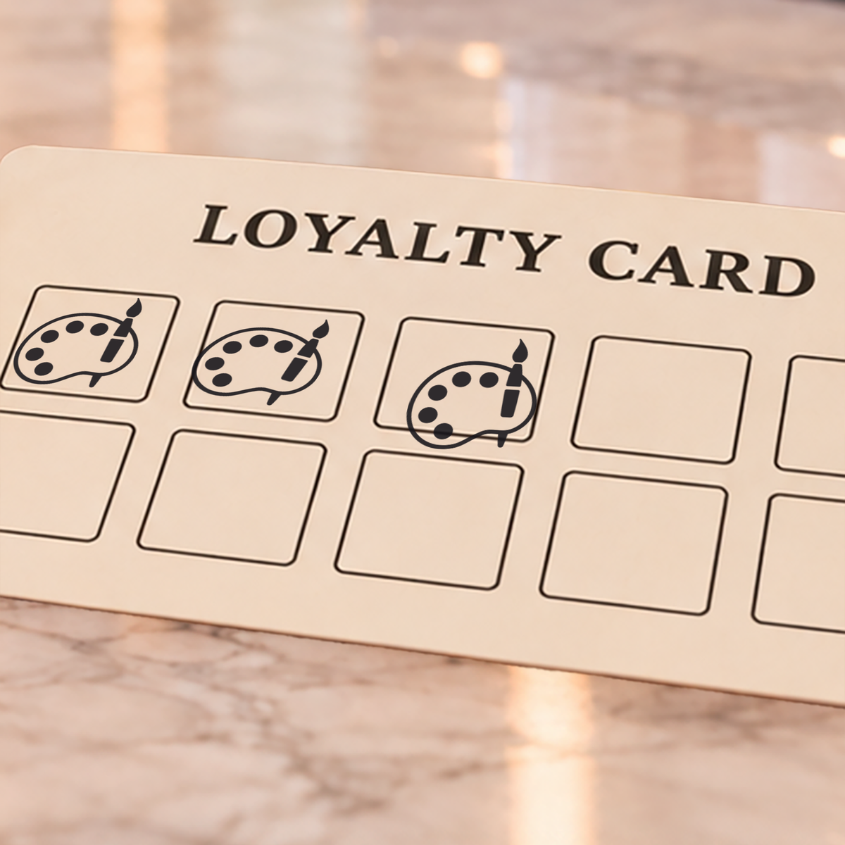 Close-up of black paint palette and brush impressions on an example loyalty card