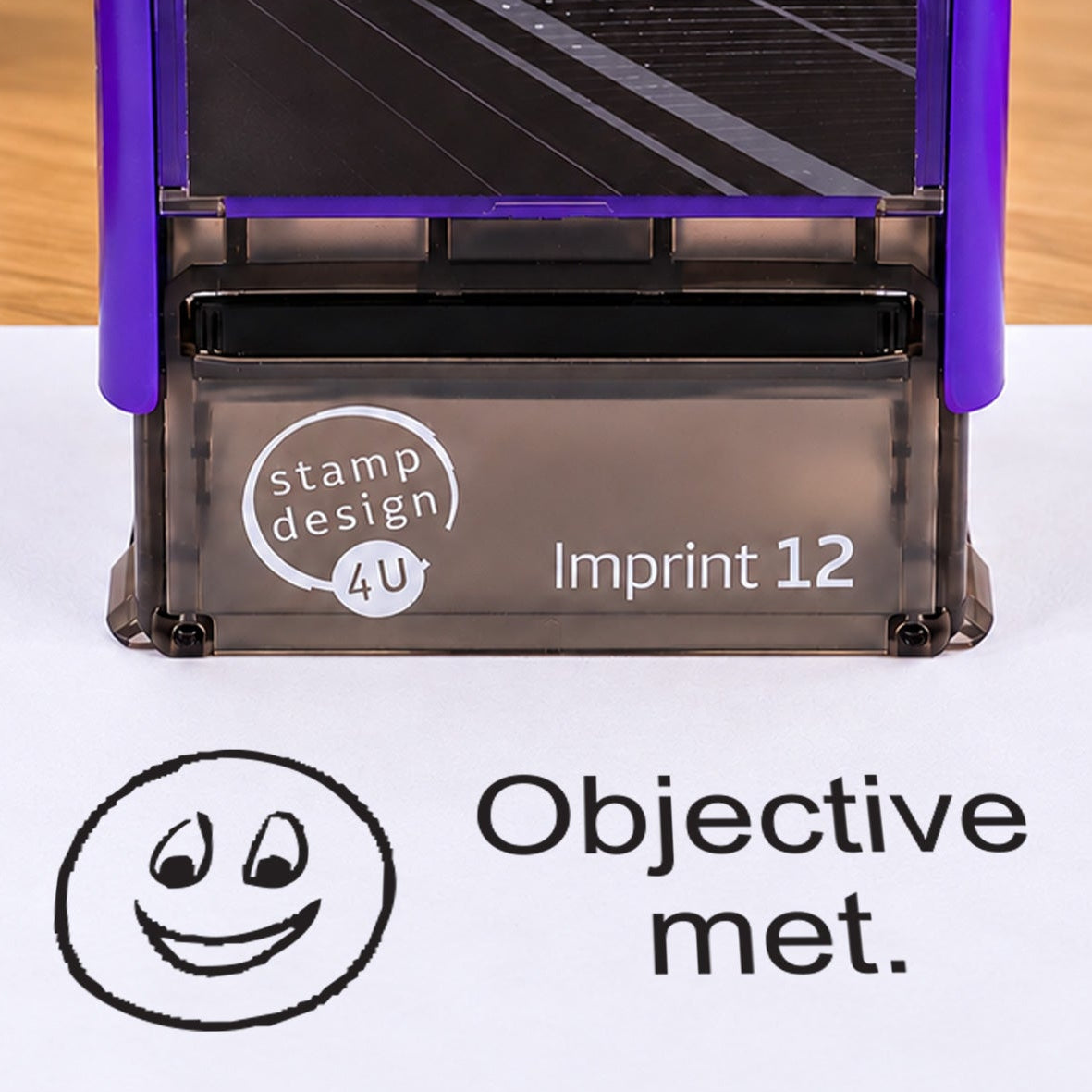 Objective Met teacher stamp: close-up of the pictured Imprint 12 casing and black smiling-face impression