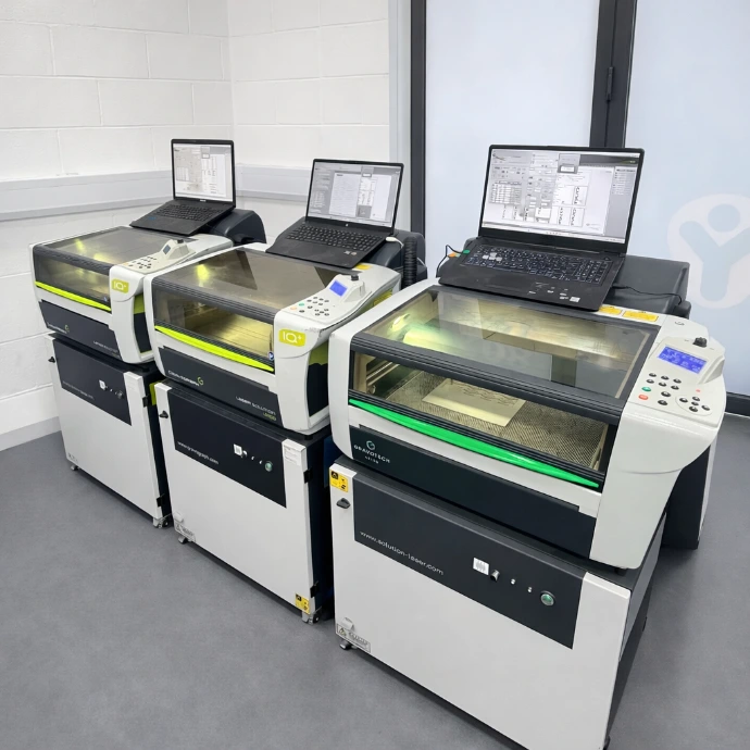 Three production machines with laptops in the StampDesign4U workshop.